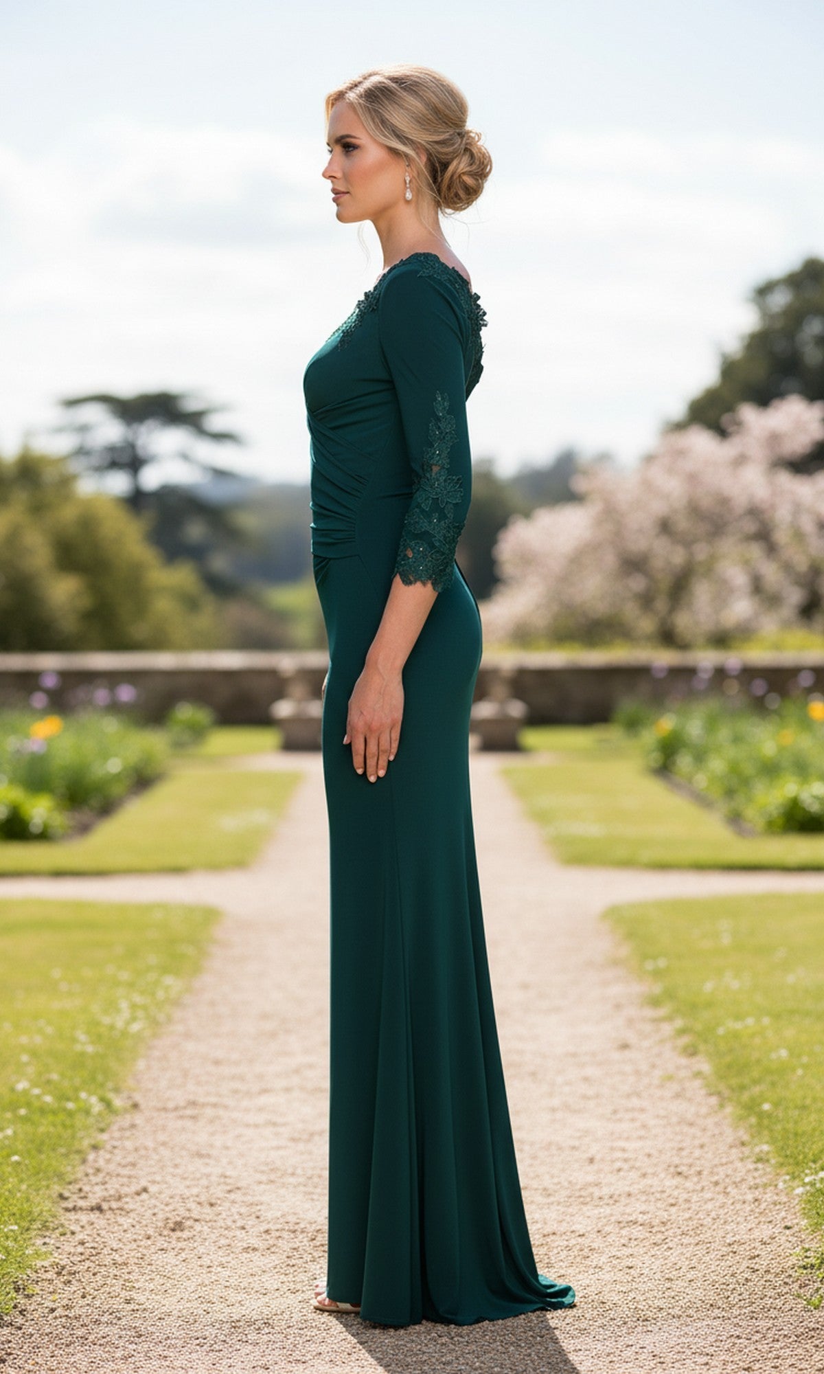A woman wearing the La Femme 33658 long prom dress with a sheath silhouette and lace sleeves stands sideways on a garden pathway, surrounded by lush greenery and trees.